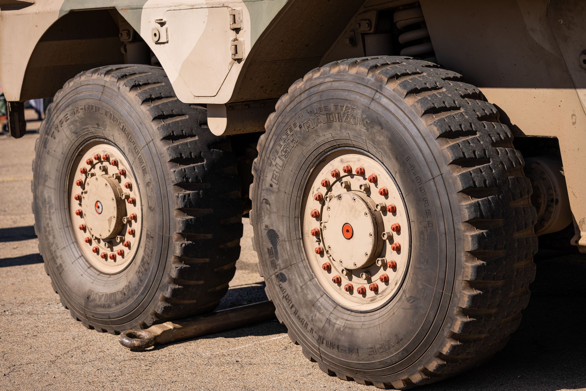 Detailed view of large military vehicle tires on an outdoor pavement.
