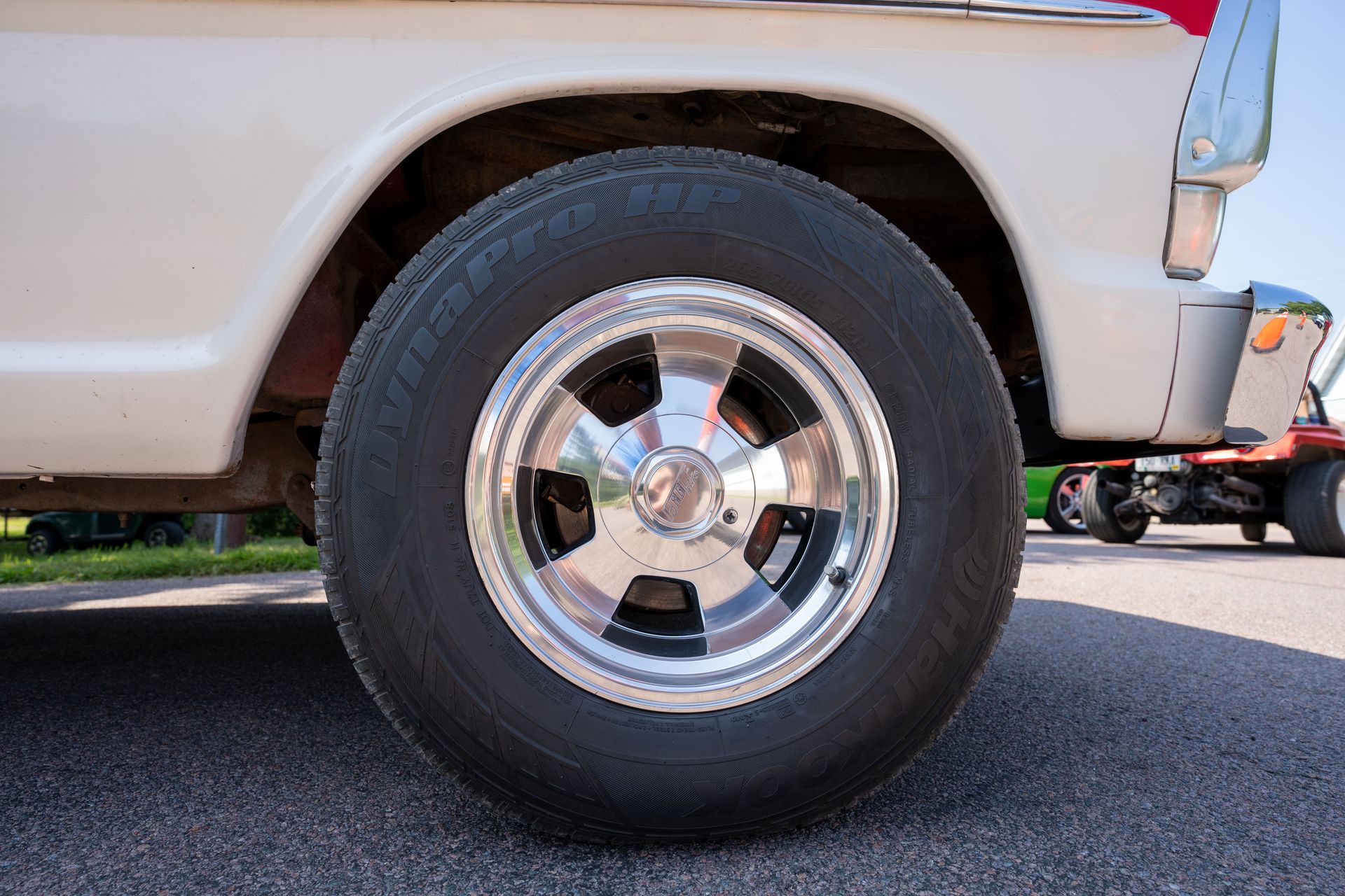 Detailed view of a classic car wheel with chrome rim and DynaPro tire on a sunny day.