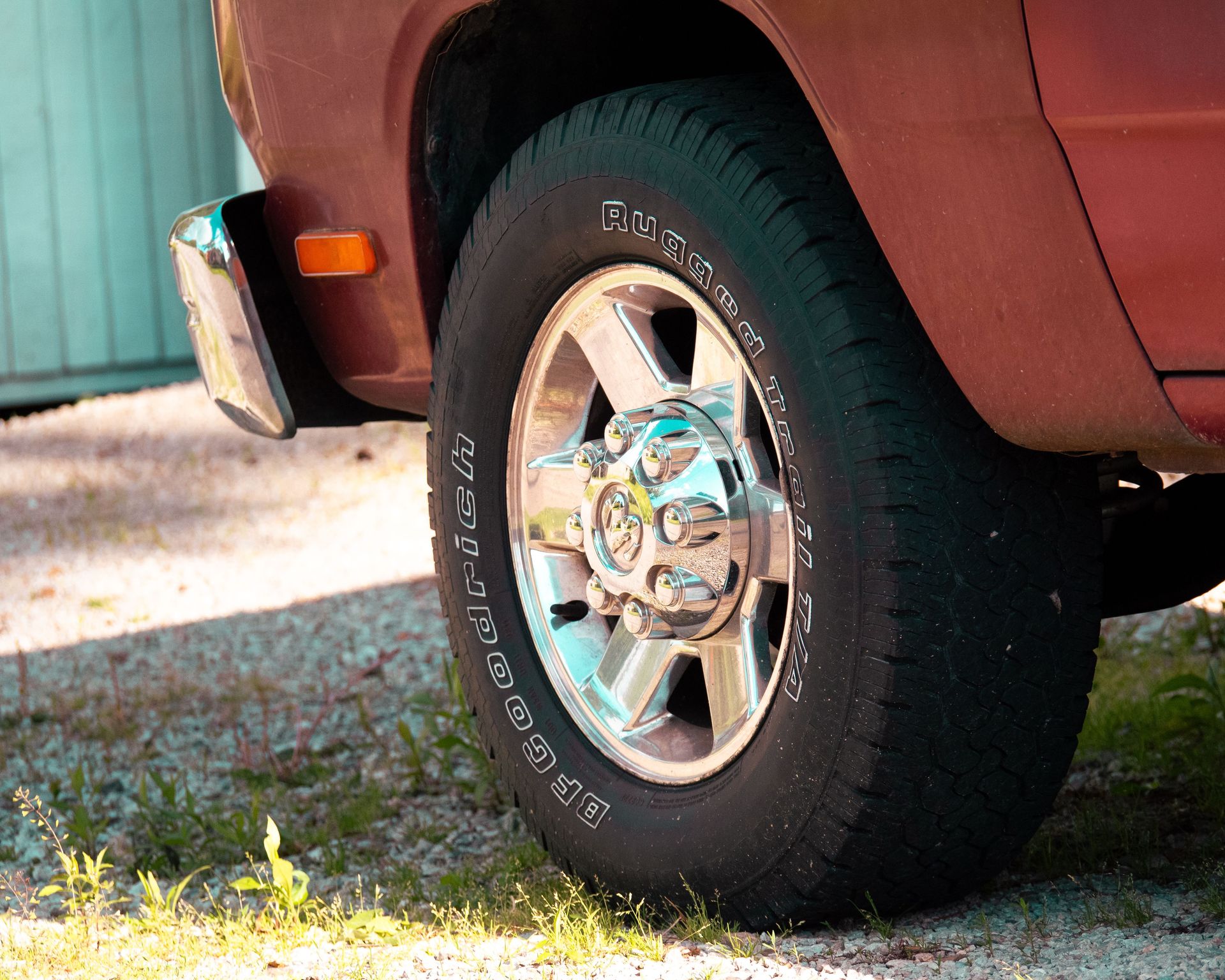 Shiny chrome truck wheel and tire on gravel, highlighting automotive detail.
