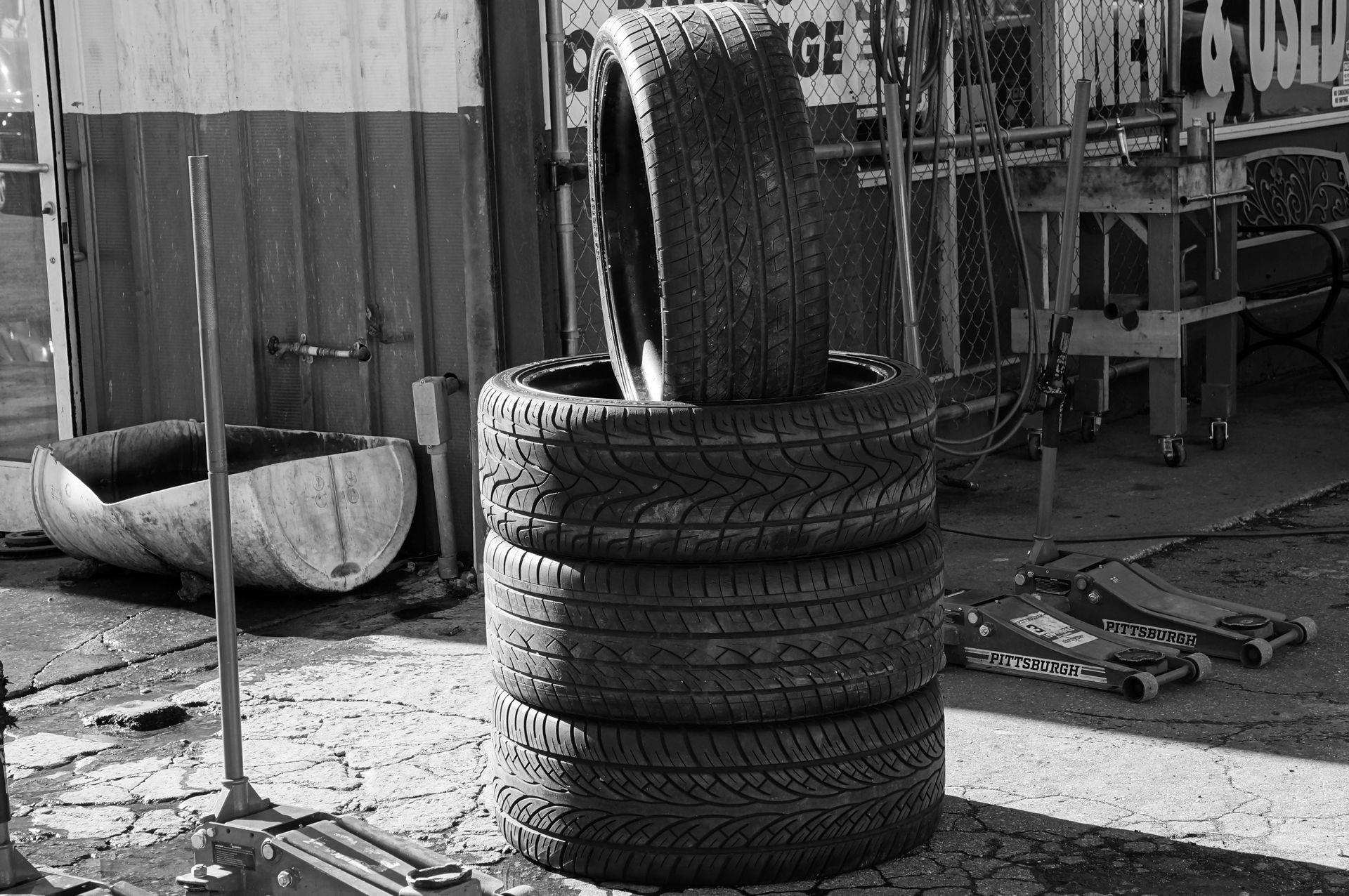Black and white photo of stacked tires in a garage environment highlighting industrial themes.